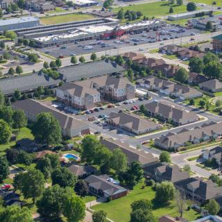 An aerial view of a suburban residential neighborhood with houses, streets, and greenery.