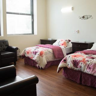 A cozy bedroom with two beds and floral bedding alongside comfortable armchairs.