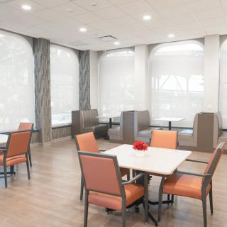 A modern dining area with tables and chairs, featuring ample natural lighting.