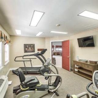 A well-equipped fitness room featuring a treadmill, stationary bike, and television.