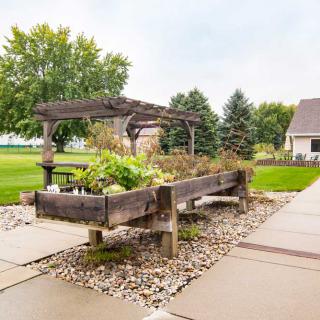 A serene garden scene with a raised bed and pergola on a well-maintained pathway.