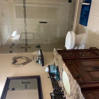 A modern bathroom with a glass shower, wooden vanity, and decorative elements.