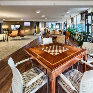 A modern lounge area featuring a chessboard table and comfortable seating.