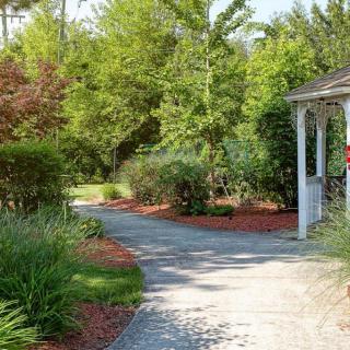 A scenic garden pathway lined with shrubs and trees leading to a gazebo.