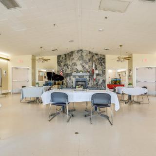 A spacious event room featuring a piano and tables set with chairs, highlighted by a decorative wall mural.