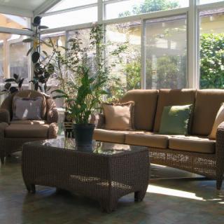 A cozy sunroom with comfortable furniture and lush indoor plants, bathed in natural light.