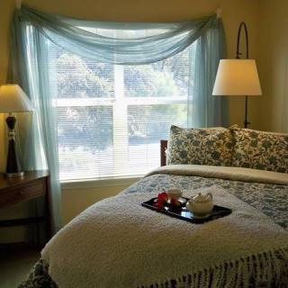 A cozy bedroom with a large window, soft lighting, and elegant decor.