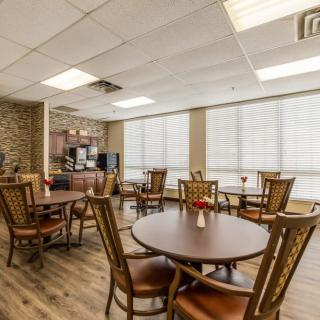 A well-lit dining area with wooden tables and chairs, featuring large windows allowing natural light to fill the space.