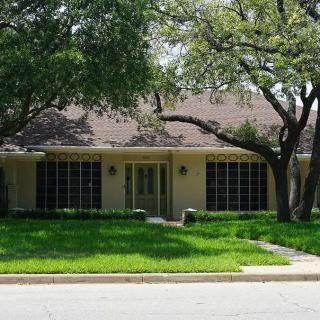 A suburban house with a well-maintained lawn and surrounding trees.