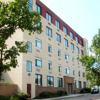 A five-story residential apartment building with surrounding trees.