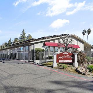 A roadside motel with a red awning and sign, surrounded by trees.
