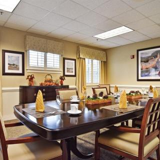 An elegantly decorated dining room featuring a large table set for meals, surrounded by chairs and adorned with artwork on the walls.
