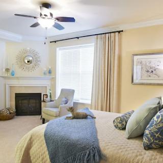 A beautifully designed bedroom featuring soft light colors, a comfortable bed, and a cozy seating area.
