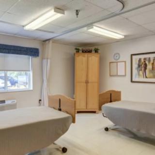 A hospital room with two beds, a window, and a cabinet.
