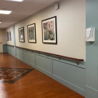 A hallway with framed artwork on the walls and a wooden floor.