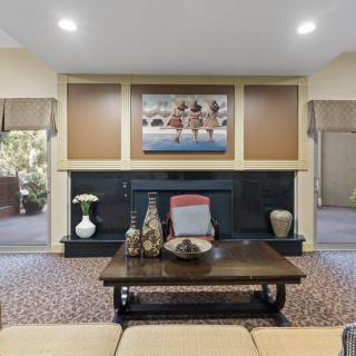 A cozy living room featuring a central fireplace, decorative items on a coffee table, and artwork displayed above.