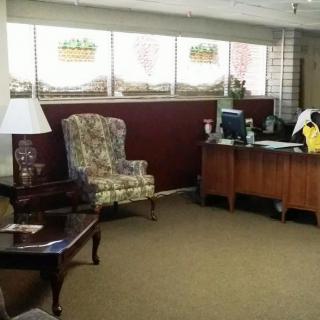 A quiet office lobby with a desk and floral armchair.