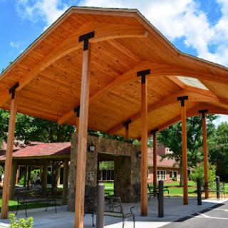 A beautifully designed wooden pavilion surrounded by greenery.