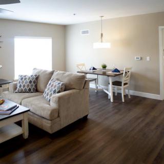 A cozy living and dining area with a modern design, featuring a comfortable sofa and hardwood floors.