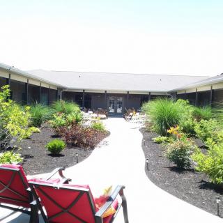 A beautifully landscaped courtyard with a pathway and red chairs.