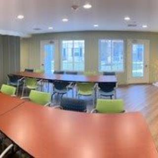 A well-lit conference room with tables and chairs arranged for a meeting.