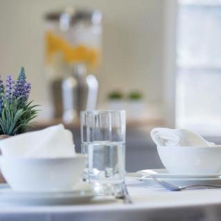 A neatly arranged table with bowls, napkins, and a glass of water, accompanied by a small potted plant.