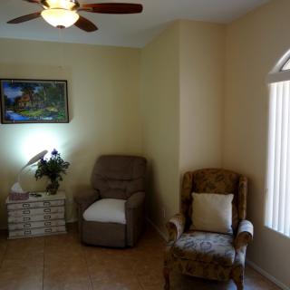 A cozy living room featuring two armchairs, a lamp, and a painting on the wall.