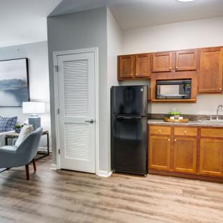 A modern apartment interior with a compact kitchen area featuring wooden cabinets and a living space.