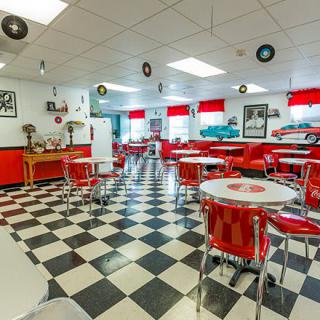 A retro 1950s-style diner with red decor and a checkered floor.