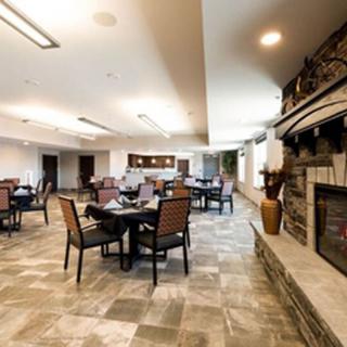 A cozy dining area with a modern interior, featuring multiple tables and a stone fireplace.