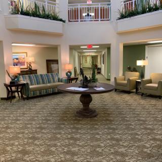 A spacious lobby area with sofas, a central table, and decorative plants.