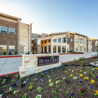A modern residential building with a landscaped garden and vibrant flowers in the foreground.