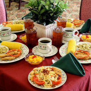 A dining table set with plates of pasta, side dishes, and beverages.