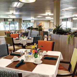 An elegant dining area with neatly set tables and colorful chairs.