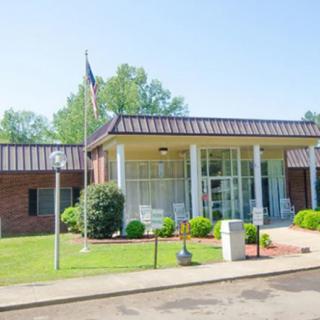A small brick building with a flagpole and landscaped front area under a clear sky.
