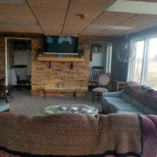A cozy living room with a brick fireplace, couches, and a television.