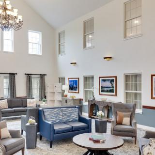 A spacious and elegantly designed living room with high ceilings, featuring modern furniture and a large chandelier.