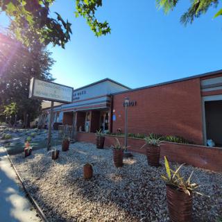 A modern architectural building surrounded by landscaped areas and potted plants under a clear blue sky.