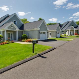 A quiet suburban neighborhood with well-maintained houses and landscaped lawns on a sunny day.