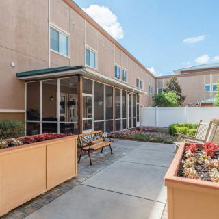 A cozy courtyard featuring benches and planters in front of a building with large windows.
