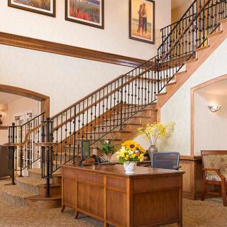 A welcoming reception area with a wooden desk, decorative flowers, and a staircase adorned with artwork.