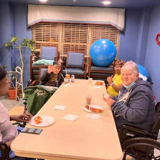 A group of elderly individuals enjoying snacks and conversation in a cozy indoor setting.