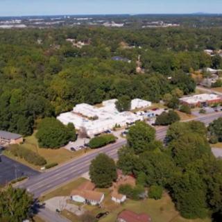Aerial view of a suburban area with trees and buildings lining the road.