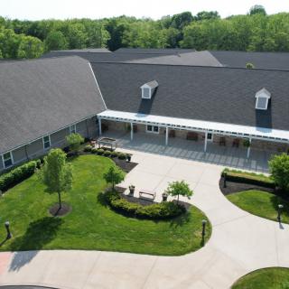 Aerial view of a large building with a landscaped garden and driveway.