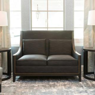 A modern sofa placed in a well-lit living room with two side tables and large windows.