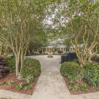 A serene garden pathway surrounded by lush trees and well-maintained landscaping.
