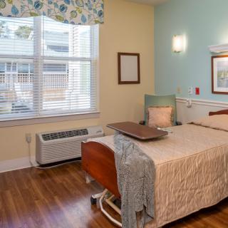 A hospital room with a bed, window, and chair, featuring a comforting ambiance.