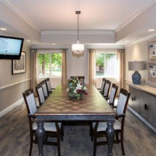 A beautifully designed dining room featuring a long wooden table, elegant chairs, and ample natural light.