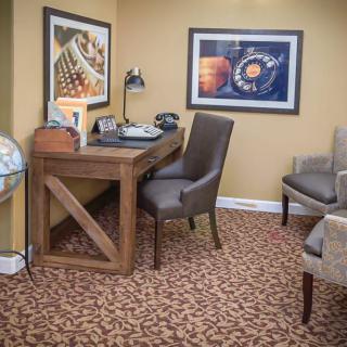 A cozy office space featuring a wooden desk with a typewriter, complemented by framed artwork and a globe.