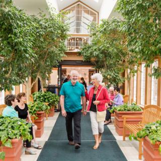A couple walks through an indoor pathway lined with lush greenery.
